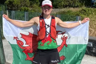 Menna in her running gear holding up a flag of Wales